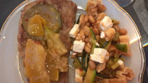 Zucchini-Chutney auf Grillfleisch neben Sommersalat